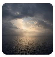 Storm clouds over dark ocean with light breaking through